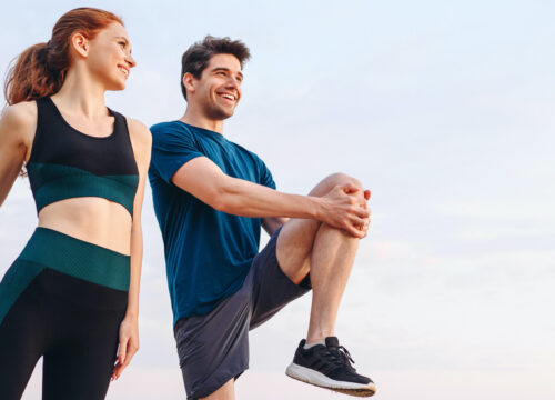 Photo of a woman and man stretching while out on a jog